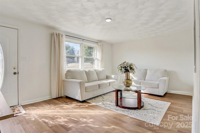 living area with a textured ceiling, wood finished floors, and baseboards