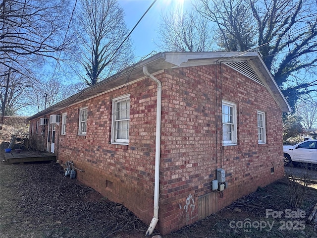 view of property exterior featuring a deck, brick siding, and crawl space