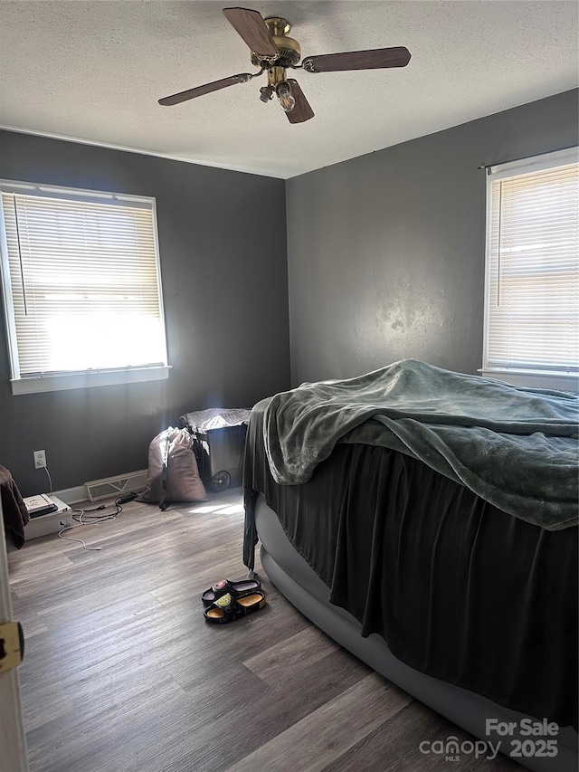 bedroom featuring ceiling fan, a textured ceiling, and wood finished floors