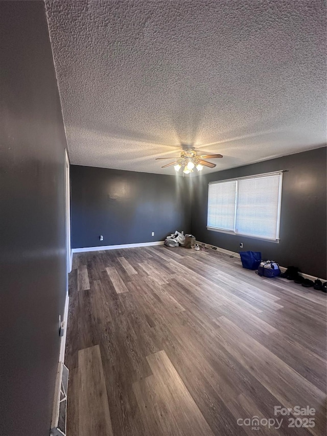 spare room featuring ceiling fan, a textured ceiling, baseboards, and wood finished floors