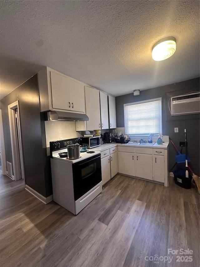 kitchen featuring a wall unit AC, under cabinet range hood, electric range, white cabinetry, and stainless steel microwave