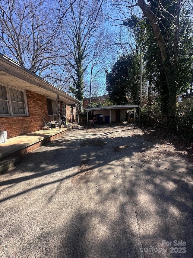 exterior space with a carport, concrete driveway, and brick siding