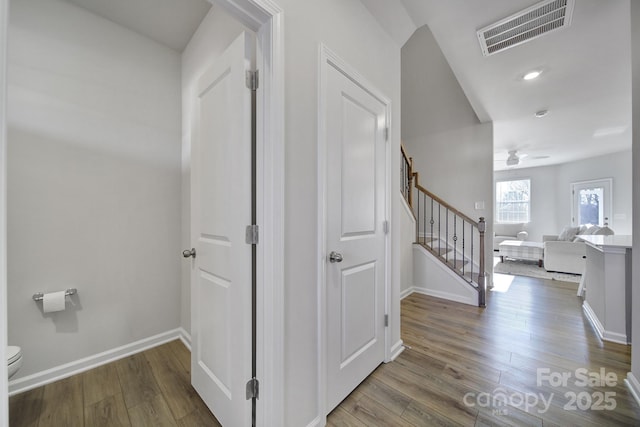 stairway with wood finished floors, visible vents, and baseboards