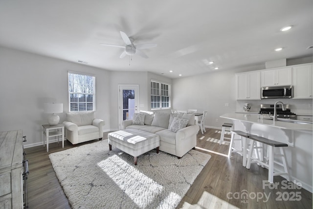 living area featuring dark wood-type flooring, recessed lighting, visible vents, and baseboards