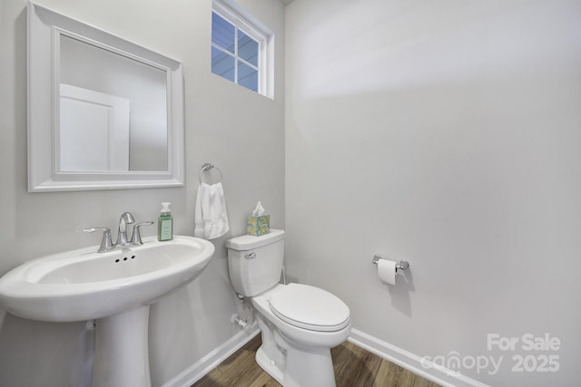 half bath featuring toilet, wood finished floors, and baseboards