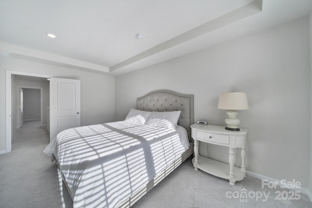 carpeted bedroom with a tray ceiling and baseboards