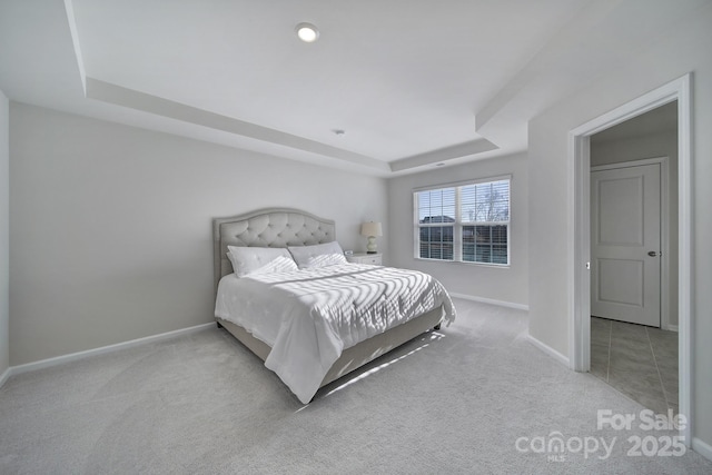 bedroom with baseboards, a raised ceiling, and carpet flooring