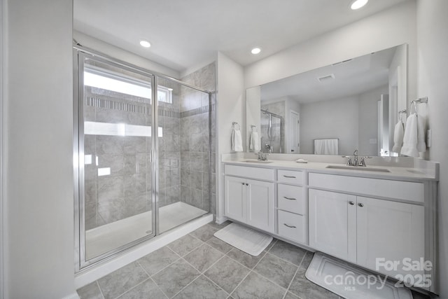 bathroom with double vanity, recessed lighting, a stall shower, and a sink