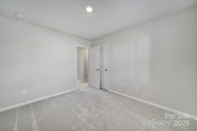 spare room with carpet flooring, visible vents, and baseboards