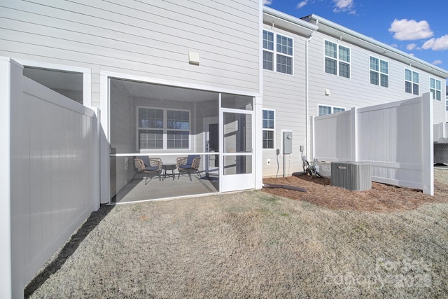 rear view of house with central air condition unit and a sunroom