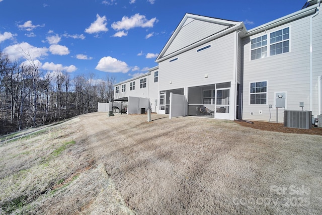 back of property with central air condition unit and a sunroom