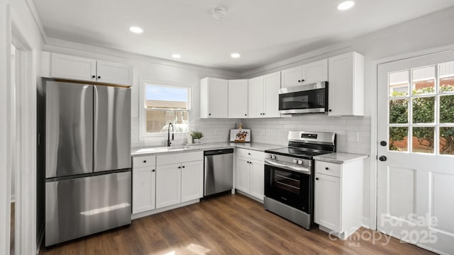 kitchen featuring dark wood-style flooring, a sink, white cabinets, appliances with stainless steel finishes, and tasteful backsplash