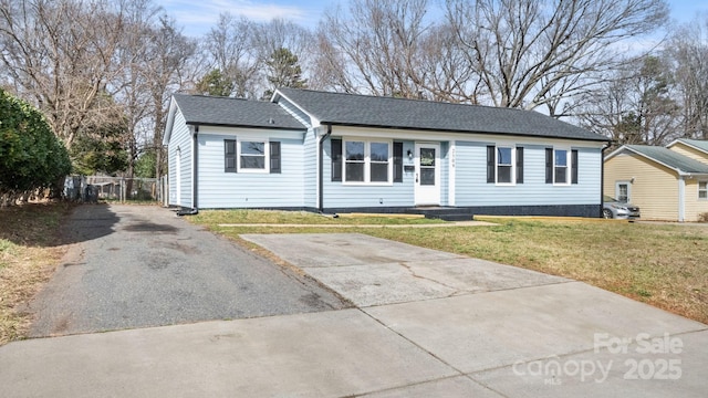 single story home featuring driveway, a shingled roof, a front yard, and fence