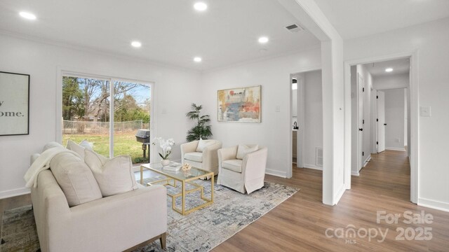 living room featuring recessed lighting, wood finished floors, visible vents, baseboards, and crown molding