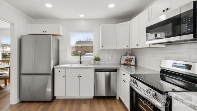 kitchen with a wealth of natural light, appliances with stainless steel finishes, white cabinets, and a sink