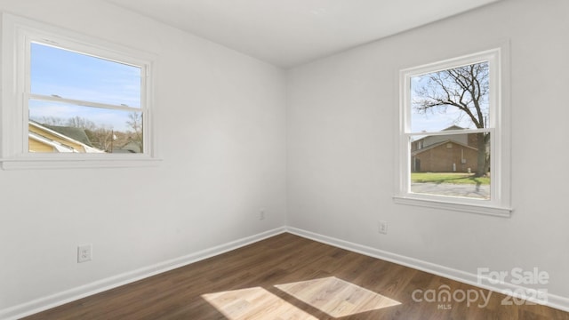 unfurnished room with baseboards and dark wood-type flooring