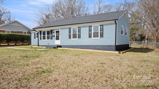 view of front of house featuring roof with shingles, a front yard, and fence