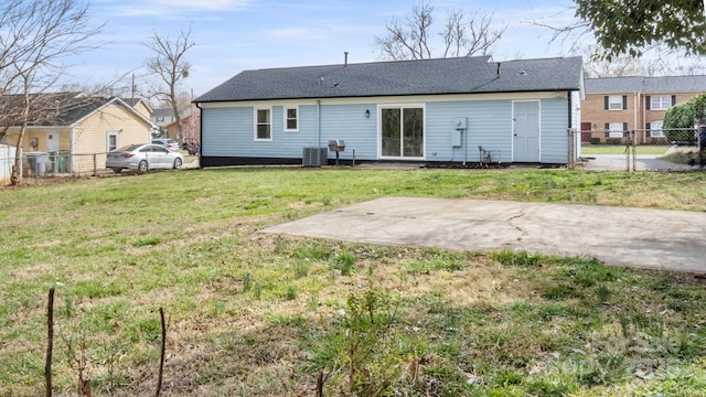 back of property with cooling unit, a lawn, and fence