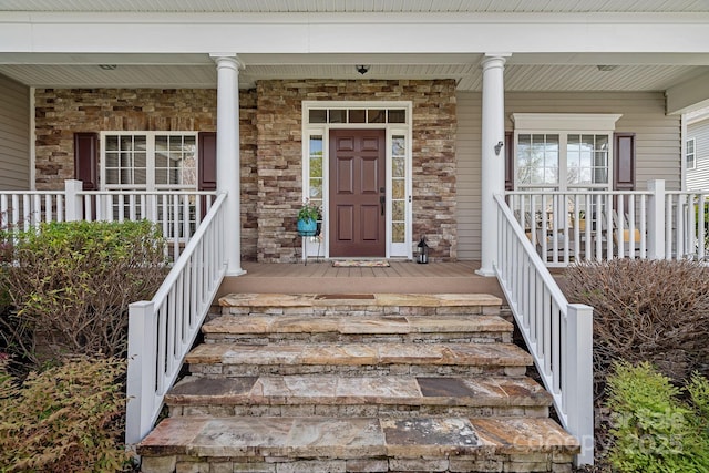 entrance to property featuring a porch and stone siding