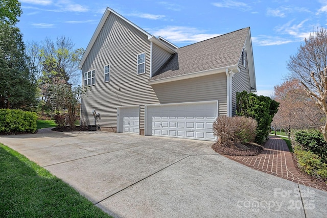 view of home's exterior with a shingled roof and driveway