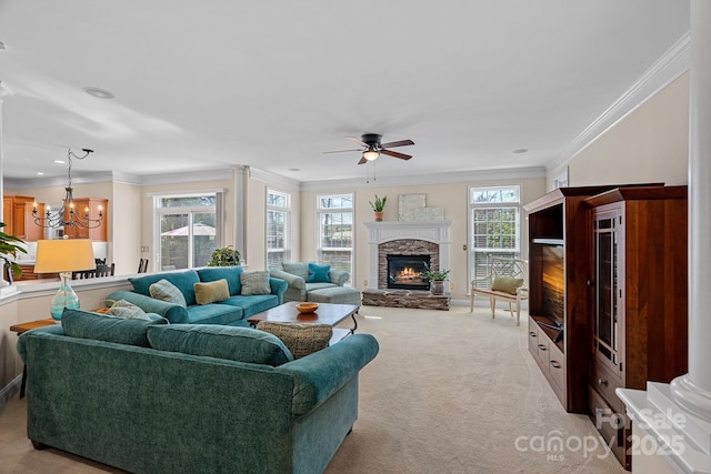 living room with light carpet, ceiling fan with notable chandelier, crown molding, and a stone fireplace