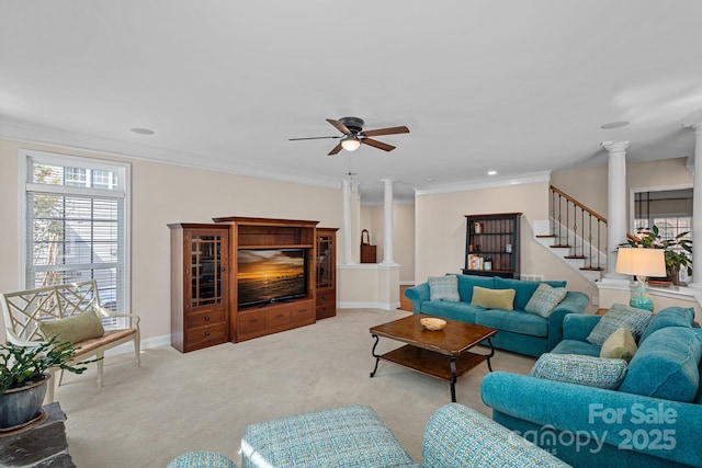 living room featuring crown molding, stairs, ornate columns, ceiling fan, and carpet