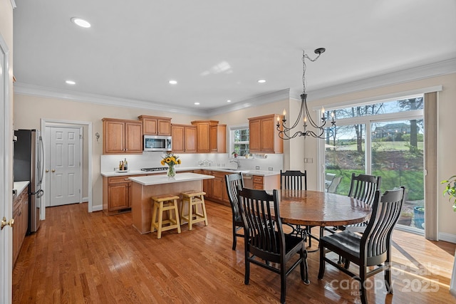 dining space featuring ornamental molding, recessed lighting, light wood finished floors, baseboards, and a notable chandelier