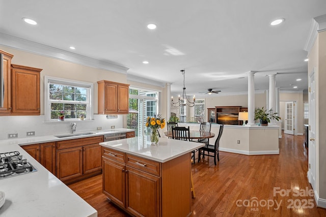 kitchen featuring brown cabinetry, crown molding, a sink, and stainless steel appliances