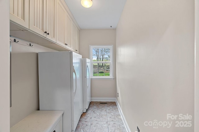 laundry area with washing machine and dryer, baseboards, and cabinet space