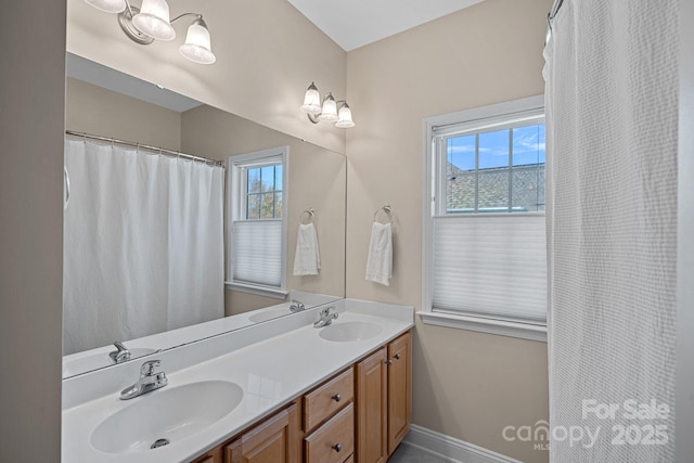 full bath featuring double vanity, baseboards, and a sink