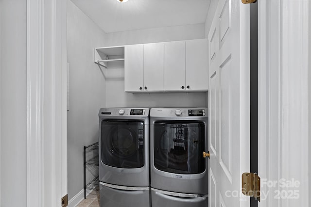 clothes washing area featuring tile patterned floors, washing machine and clothes dryer, baseboards, and cabinet space