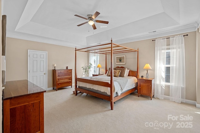 bedroom with a tray ceiling, baseboards, multiple windows, and light colored carpet