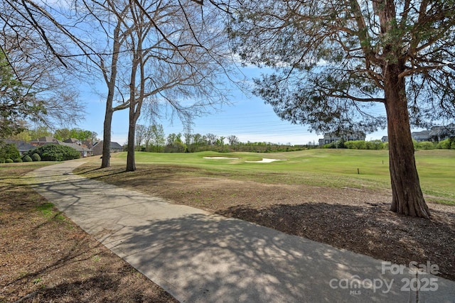 view of property's community with view of golf course and a lawn