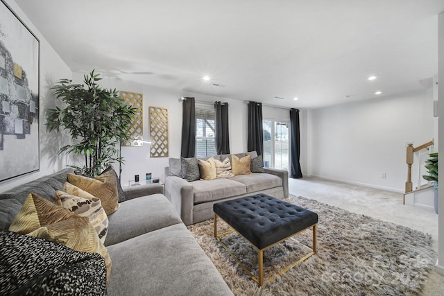 living area with recessed lighting, light carpet, baseboards, and stairs