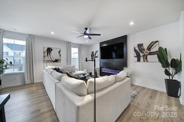 living room featuring light wood finished floors, ceiling fan, and baseboards