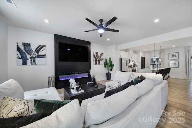 living area featuring light wood-type flooring, baseboards, visible vents, and recessed lighting