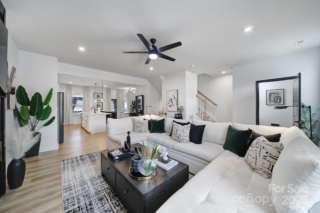 living room featuring light wood finished floors, recessed lighting, visible vents, ceiling fan, and stairs