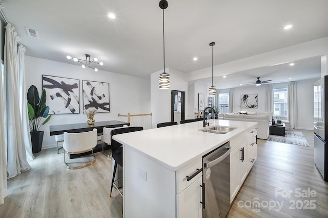 kitchen featuring visible vents, dishwasher, open floor plan, light wood-style floors, and a sink