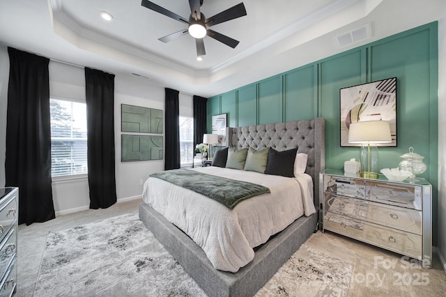 bedroom with multiple windows, a raised ceiling, visible vents, and crown molding