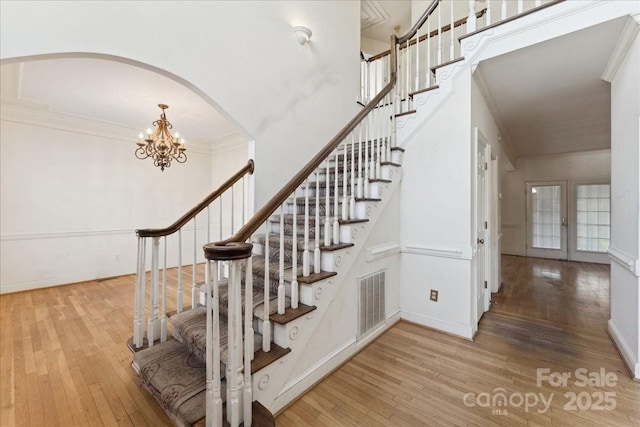 stairs with hardwood / wood-style flooring, baseboards, visible vents, and ornamental molding