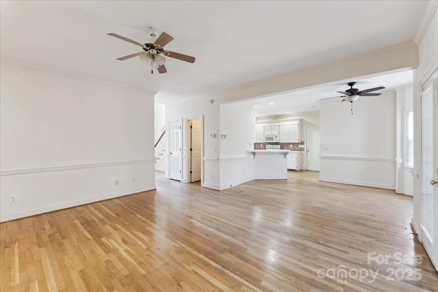 unfurnished living room featuring light wood finished floors, ceiling fan, baseboards, and crown molding