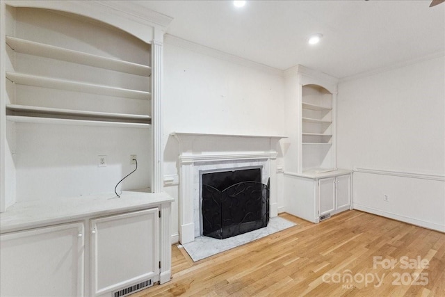 unfurnished living room with ornamental molding, visible vents, light wood finished floors, and a premium fireplace