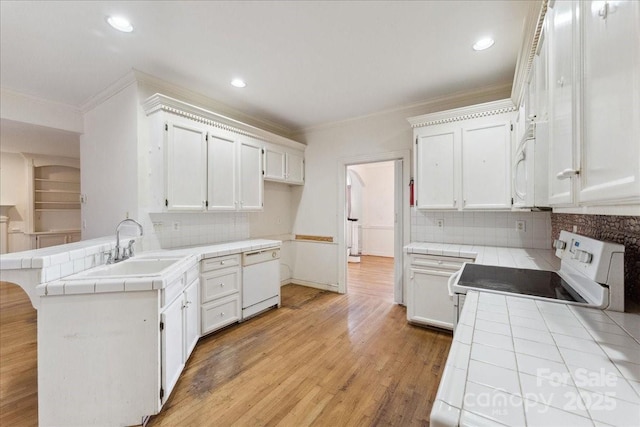 kitchen featuring light wood-type flooring, white appliances, tile countertops, and a peninsula