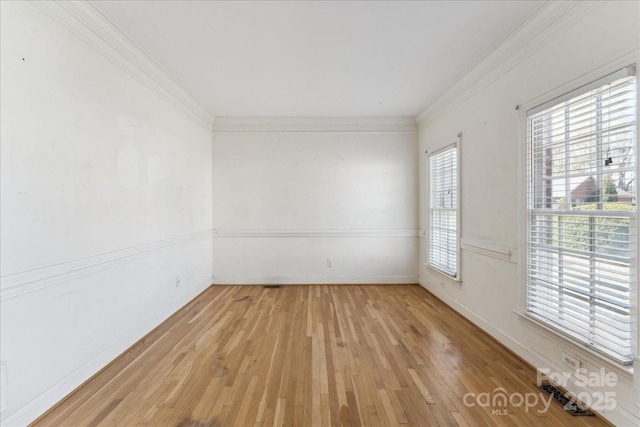 spare room with baseboards, light wood-type flooring, and crown molding