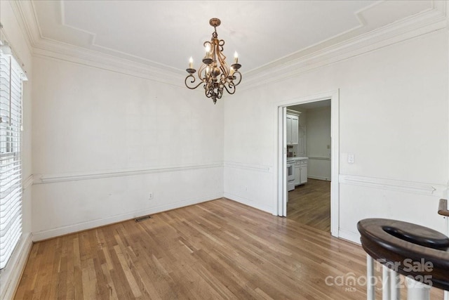 unfurnished dining area featuring a notable chandelier, wood finished floors, visible vents, baseboards, and ornamental molding