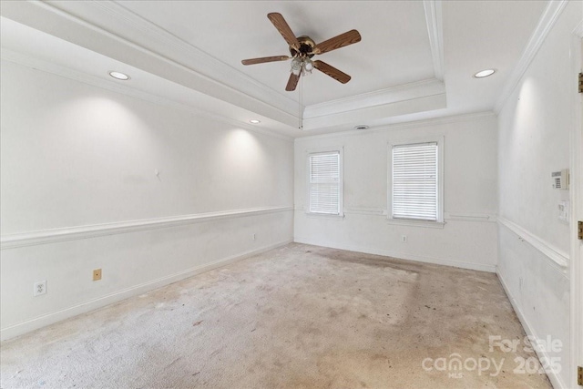 carpeted empty room with ornamental molding, a tray ceiling, ceiling fan, and baseboards