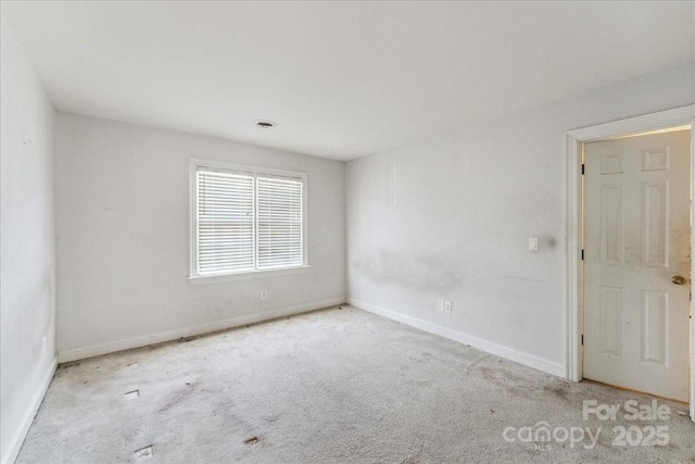 carpeted spare room with visible vents and baseboards