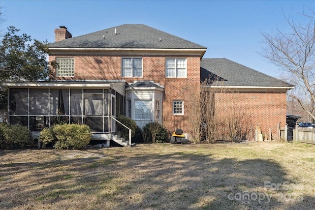 back of house with brick siding, a chimney, a lawn, a sunroom, and fence