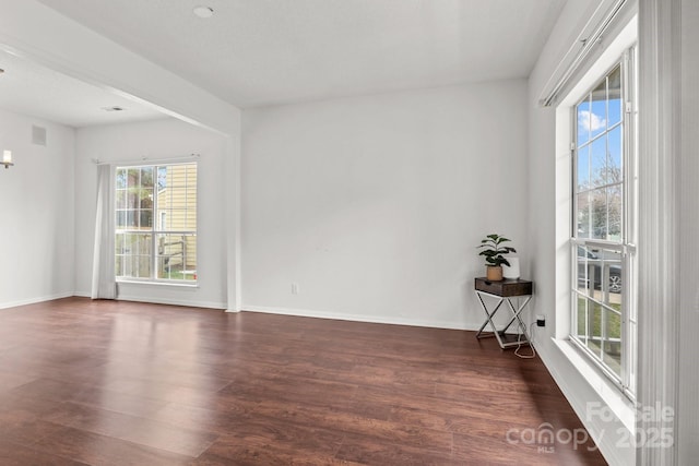 empty room featuring baseboards and dark wood-style floors