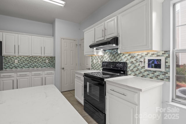 kitchen with under cabinet range hood, black range with electric cooktop, white cabinets, and light countertops